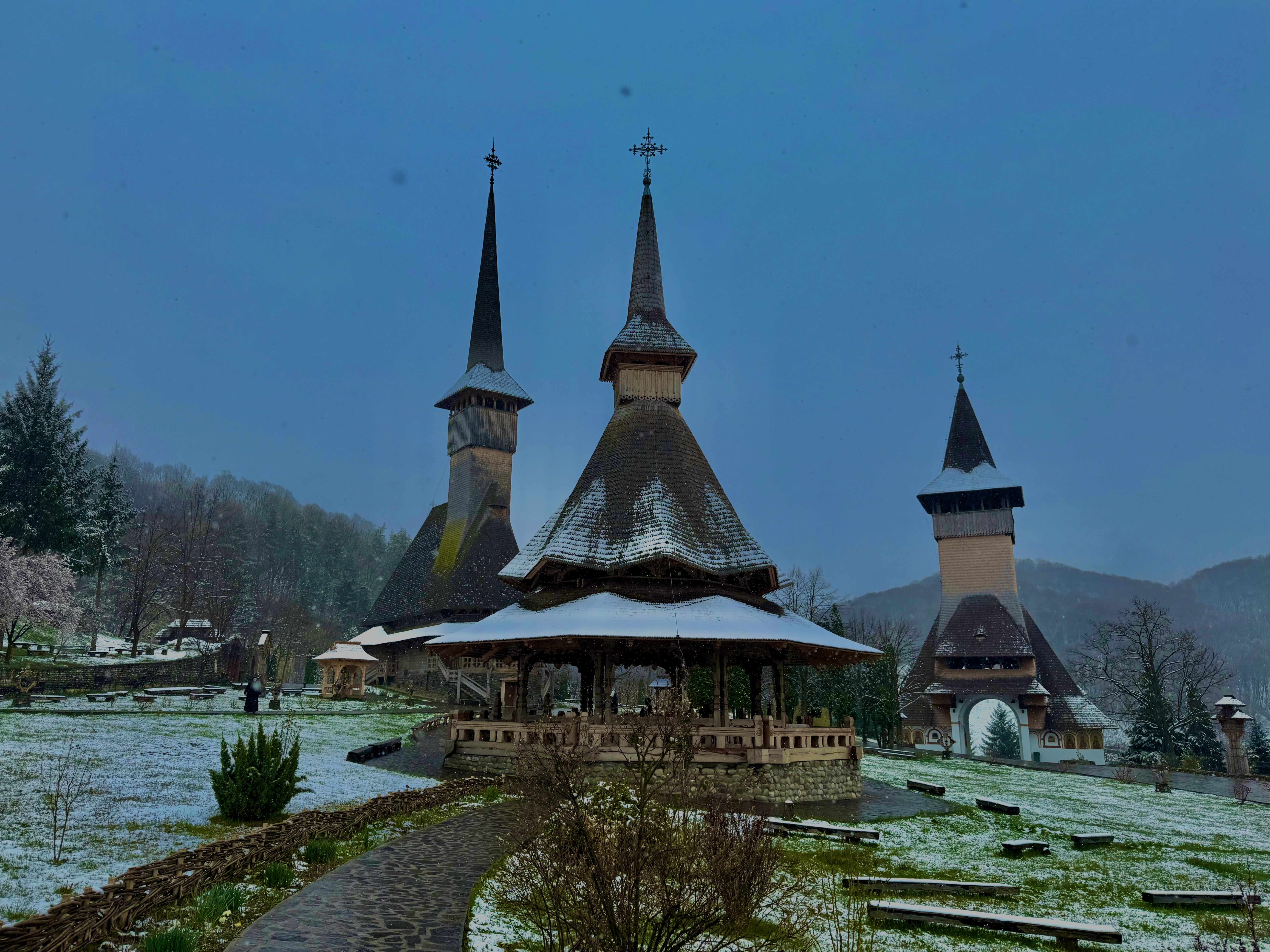 Bârsana wooden monastery complex in Maramureș under fresh snowfall, timber spires rising against a winter sky