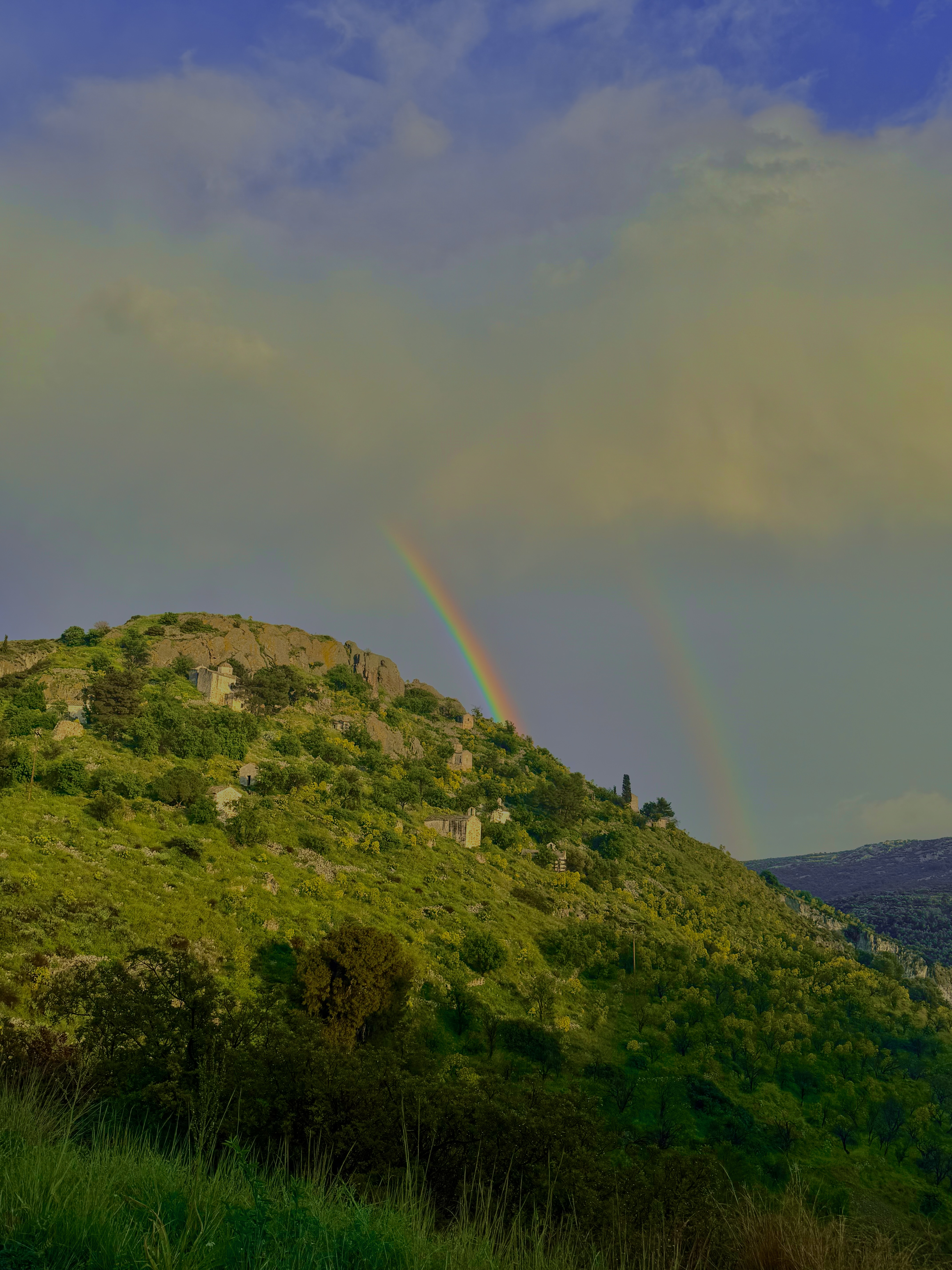 Double rainbow over a green mountainside village