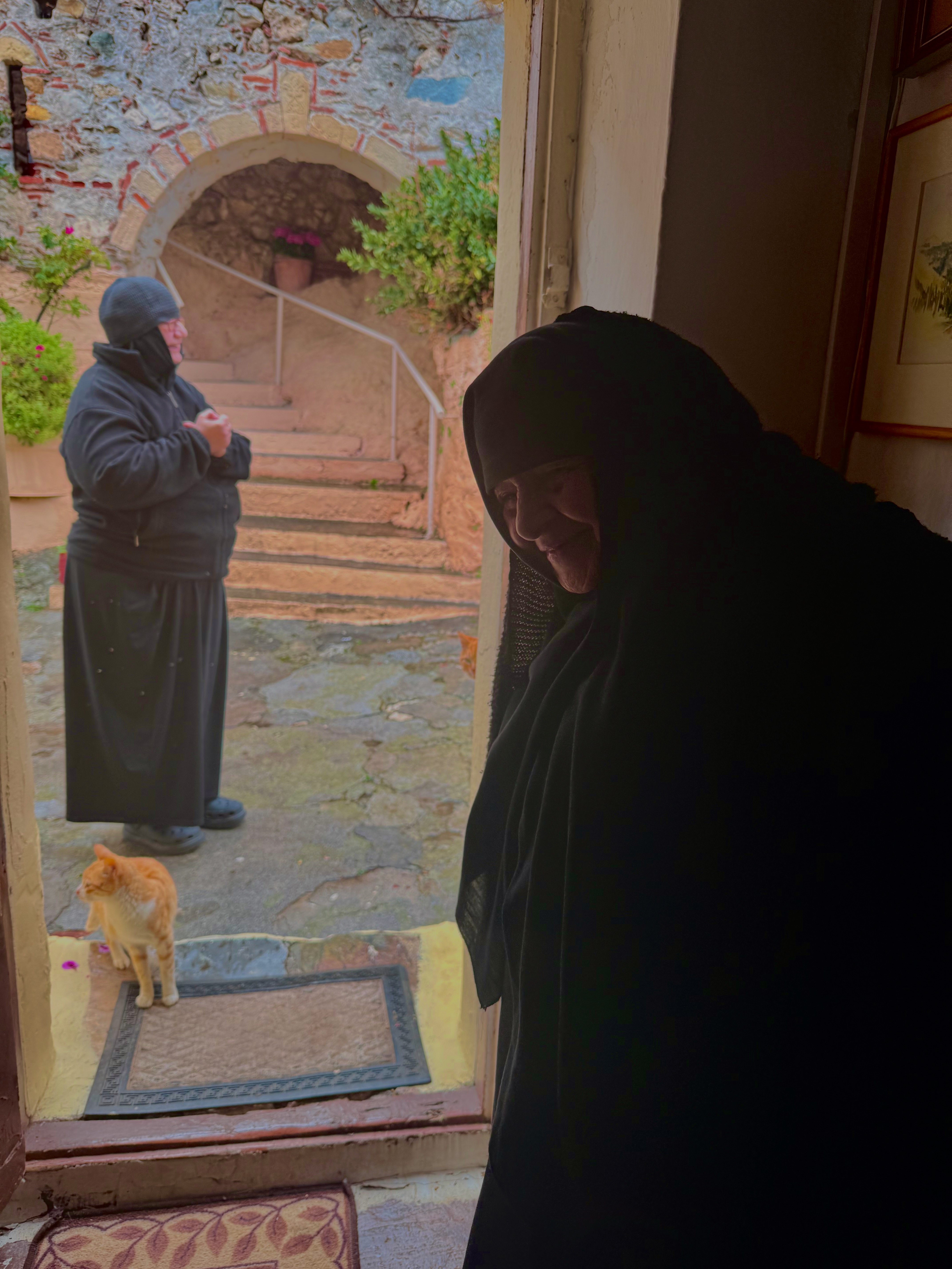 Orthodox monks in a doorway with a cat at their feet