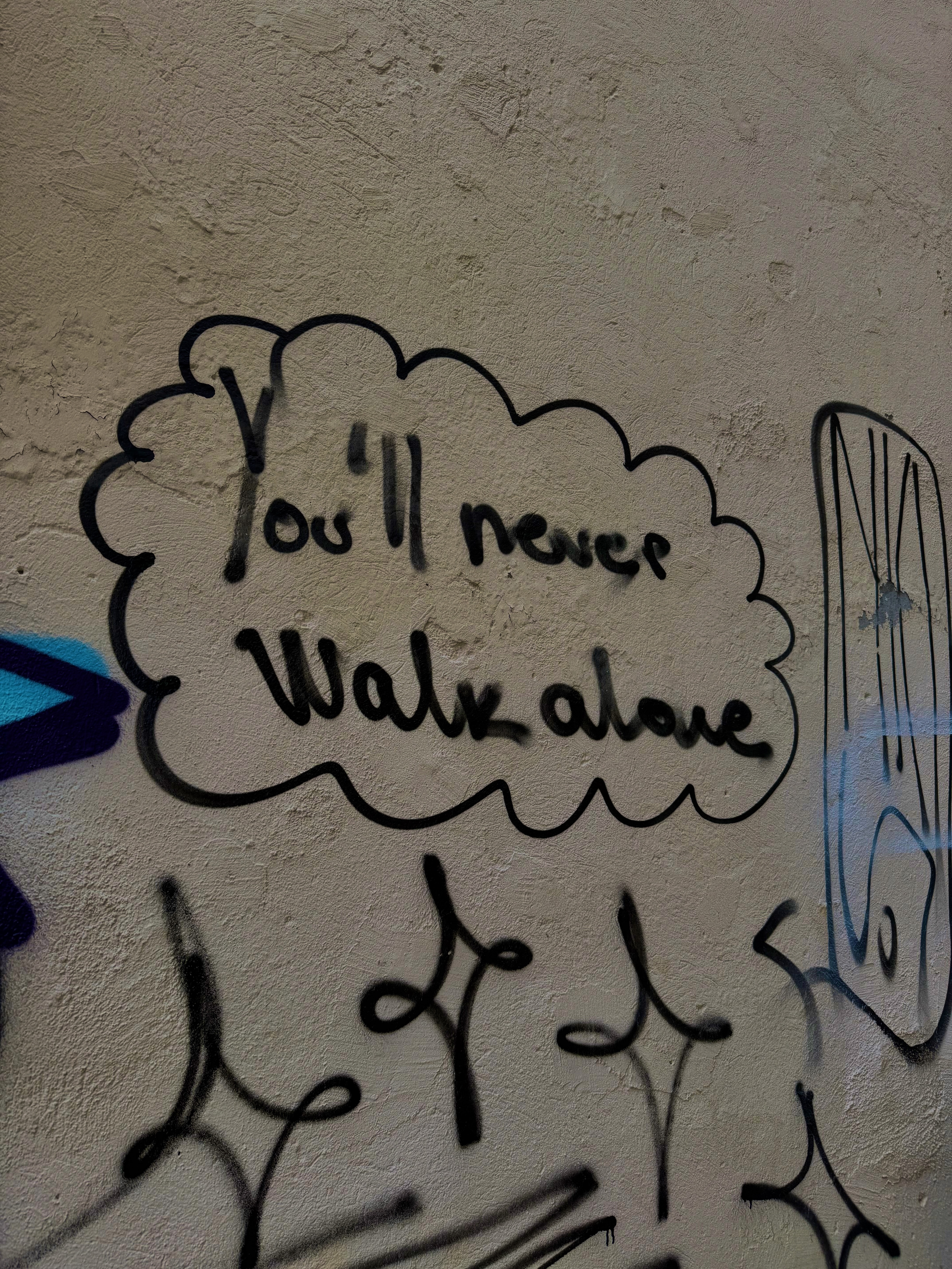 Graffiti on a wall reading 'You'll never walk alone'