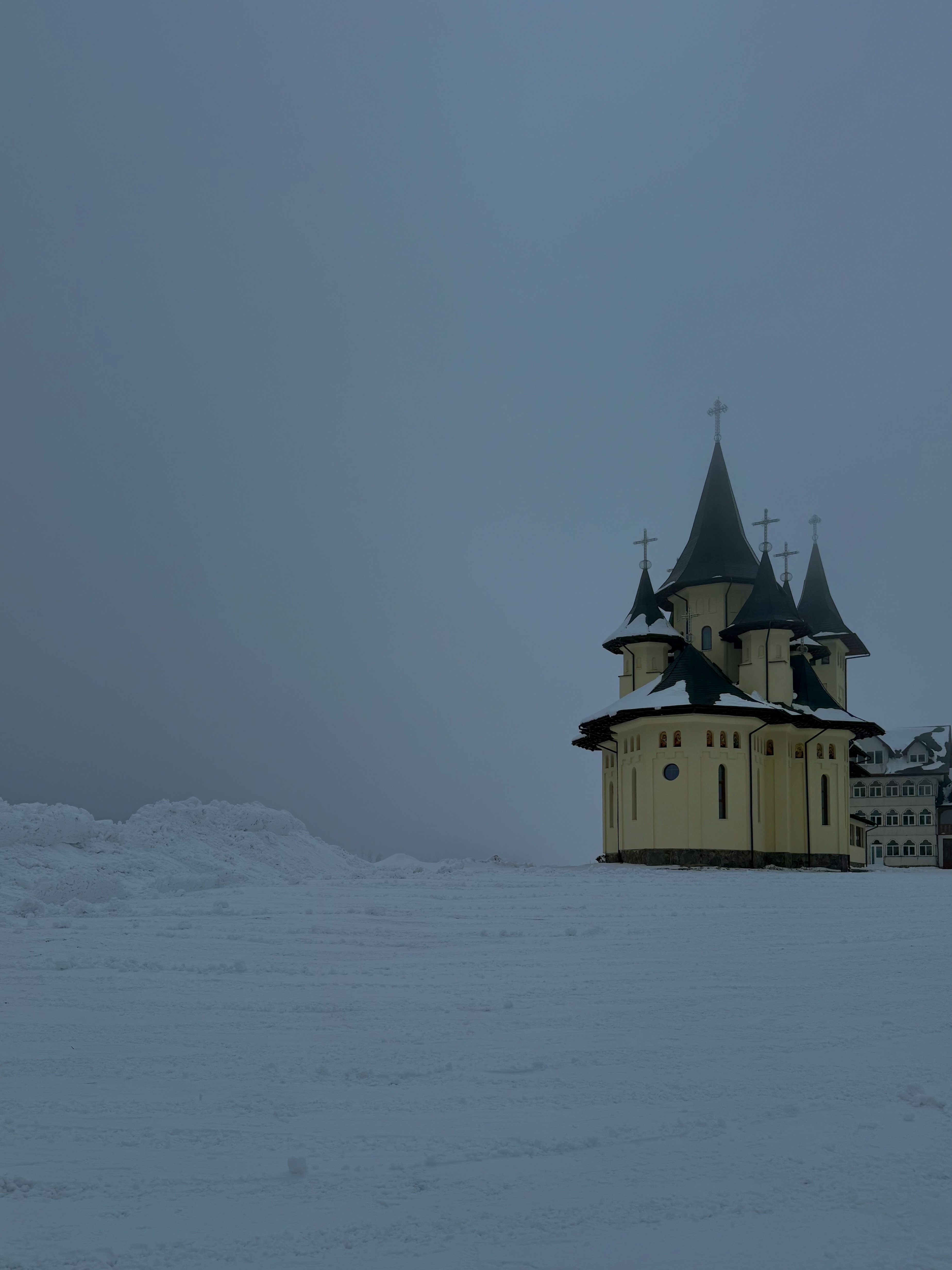Orthodox church with dark spires rising from a snow-covered plateau, Maramureș, Romania