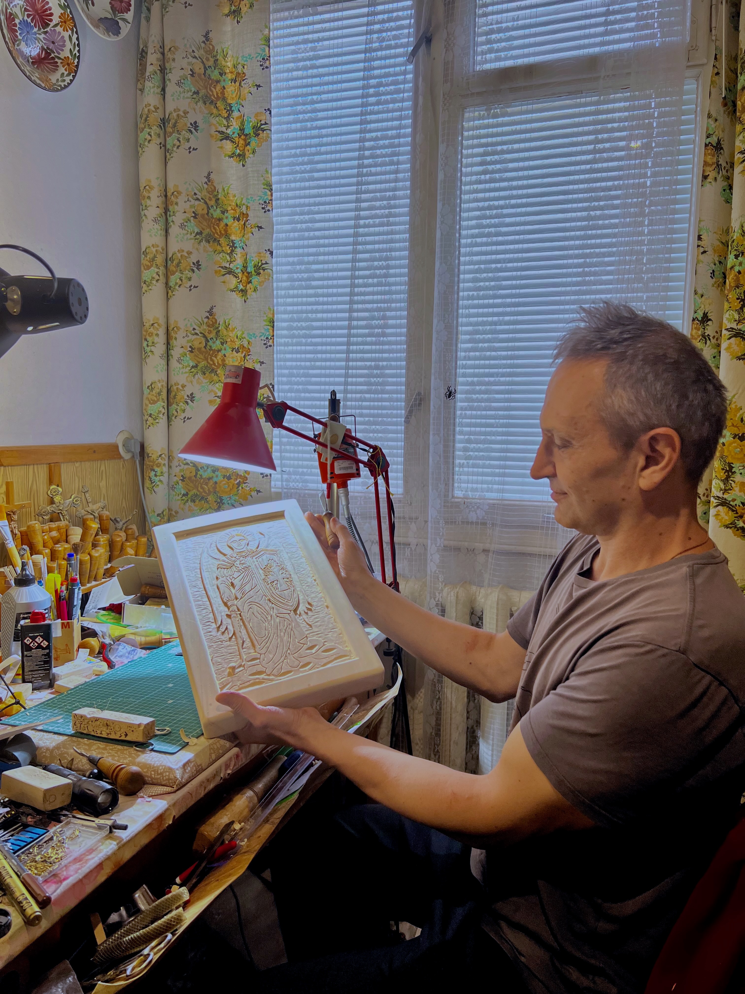 Artisan holding a hand-carved wooden icon in his studio