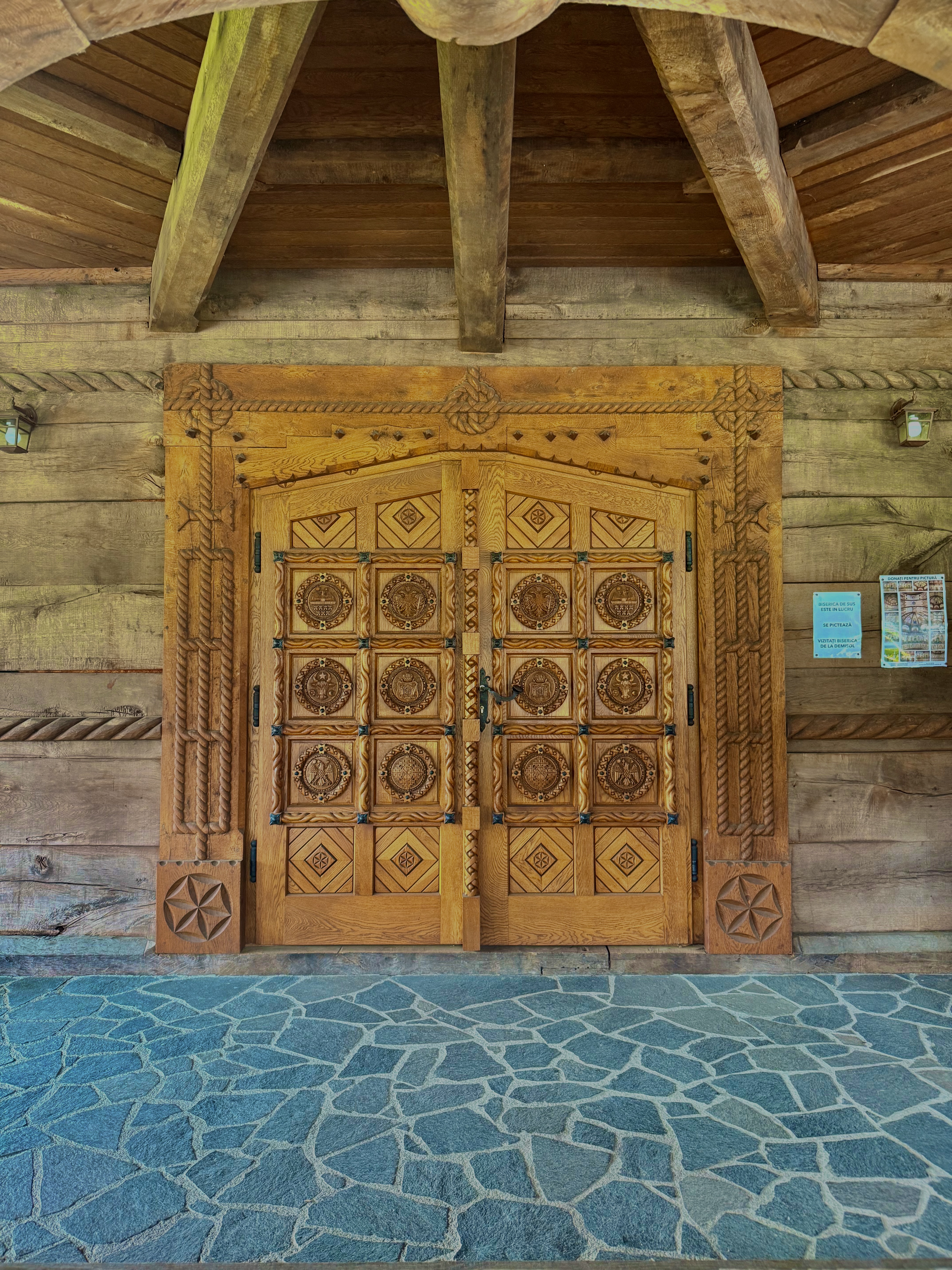 Intricately carved wooden double doors of a Maramureș church, geometric rosettes and rope motifs in aged oak