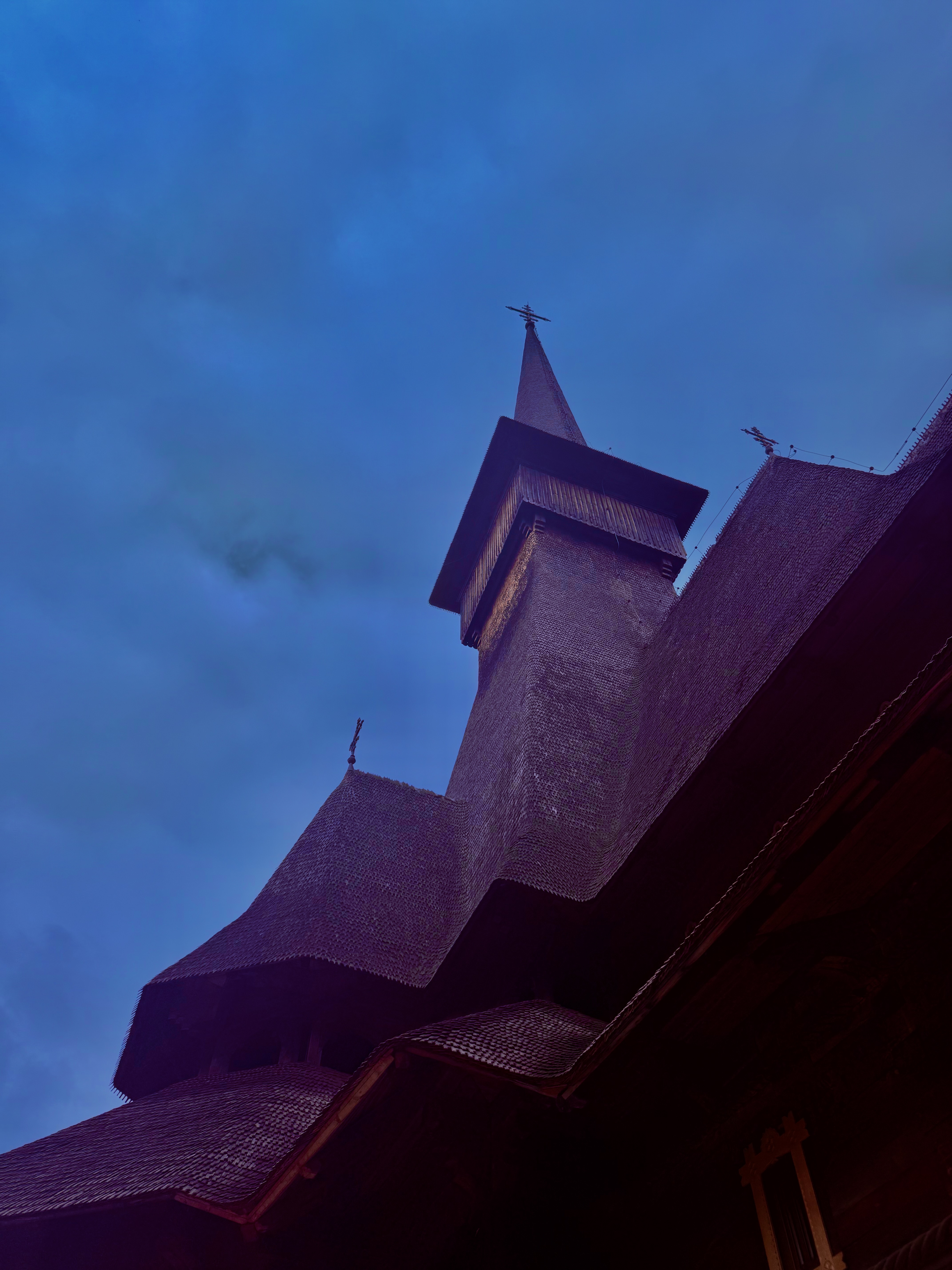 Wooden church tower rising dramatically into a deep blue twilight sky, seen from below
