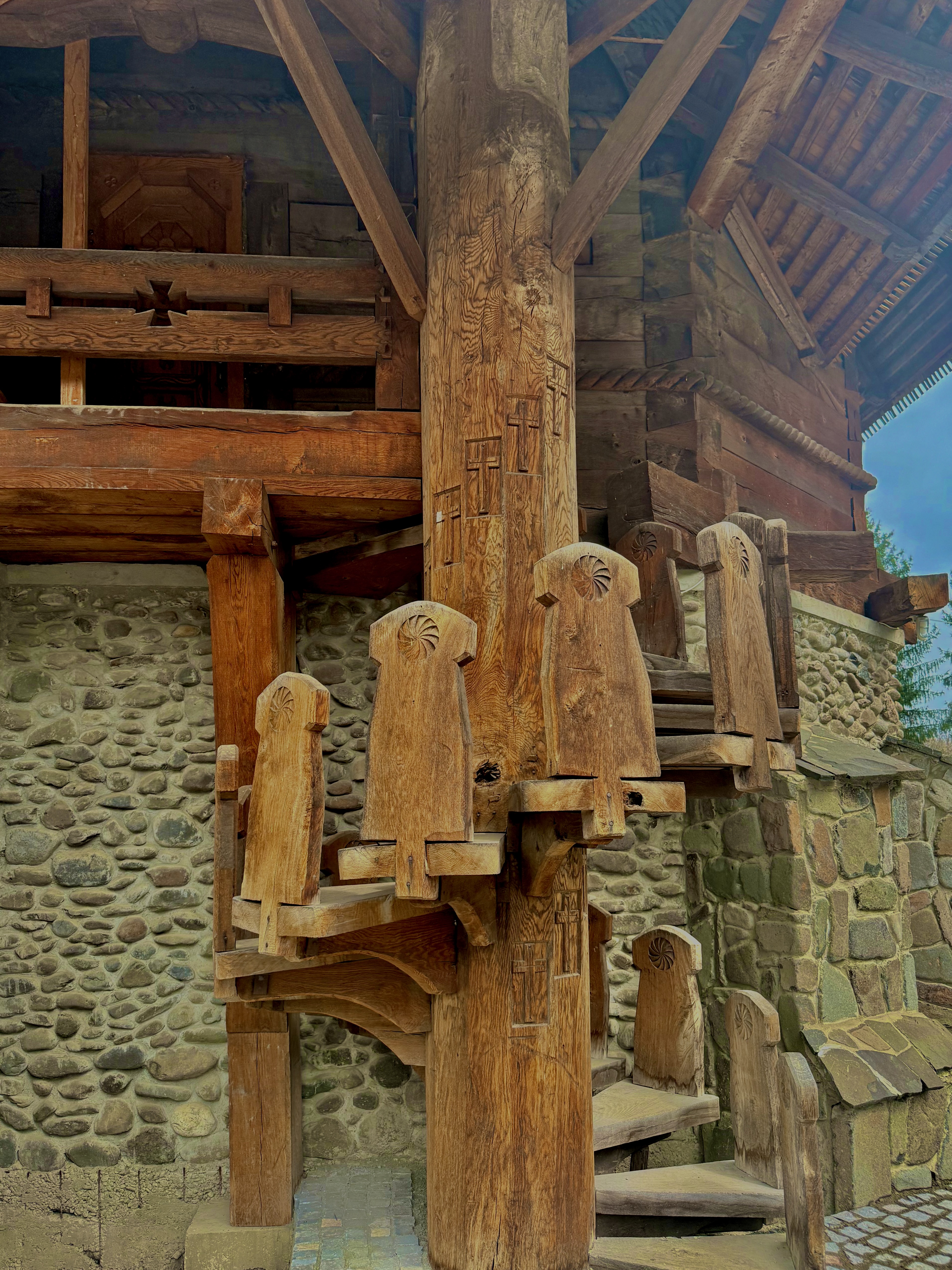 Hand-carved wooden column with decorative brackets in a monastery courtyard, stone and timber textures